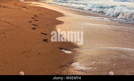 Menschliche Fußspuren im Sand am Meer Stockfoto
