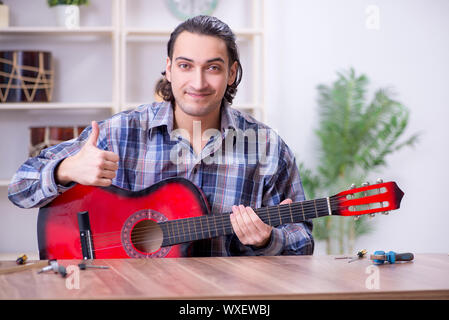 Junge schöne Handwerker Reparatur Gitarre Stockfoto