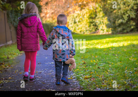 Geschwister gehen Hand in Hand im Park Stockfoto