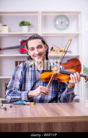 Junge schöne Handwerker Instandsetzung Violine Stockfoto