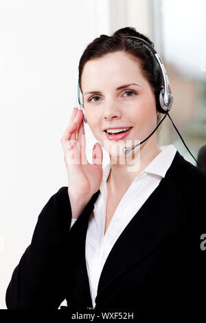 lächelnde junge weibliche Callcenter-Agent mit Kopfhörer im Büro Stockfoto