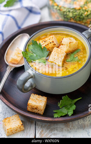 Erbsensuppe mit geräuchertem Rippchen und Croutons in eine Schüssel geben. Stockfoto