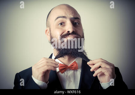 Lustige eleganten bärtigen Mann berühren Bart auf Vignettierung Hintergrund Stockfoto