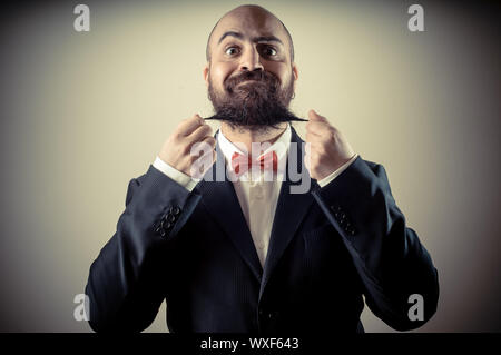 Lustige eleganten bärtigen Mann berühren Bart auf Vignettierung Hintergrund Stockfoto