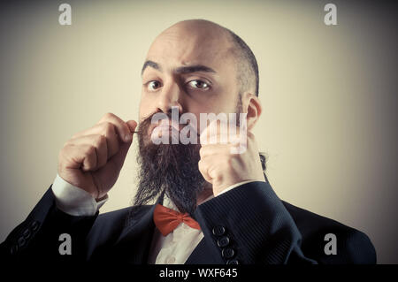 Lustige eleganten bärtigen Mann berühren Schnurrbart auf Vignettierung Hintergrund Stockfoto