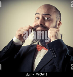 Lustige eleganten bärtigen Mann berühren Schnurrbart auf Vignettierung Hintergrund Stockfoto