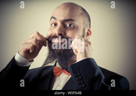 Lustige eleganten bärtigen Mann berühren Schnurrbart auf Vignettierung Hintergrund Stockfoto