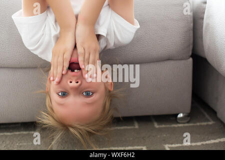 Amüsiert Funny Girl kopfüber auf der Couch zu Hause Stockfoto