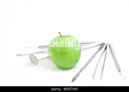 Grüner Apfel und Dentalwerkzeuge isoliert auf weiss Stockfoto