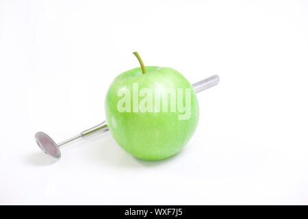 Grüner Apfel und Dentalwerkzeuge isoliert auf weiss Stockfoto