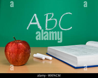 ABC auf einer Tafel mit dem Apfel, ein Buch und einige Stücke Kreide geschrieben. Stockfoto