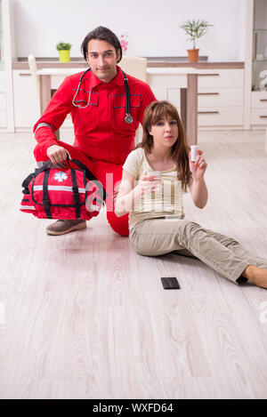 Junge männliche Sanitäter besuchen junge Frau Stockfoto