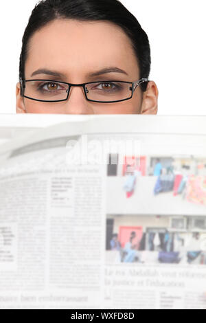 Frau in Gläsern über eine Zeitung Stockfoto