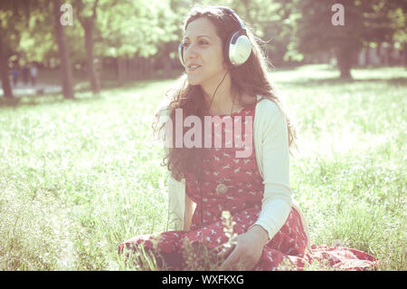 Vintage Hippie östliche frau mit Kopfhörer im Park Stockfoto