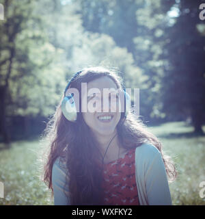 Vintage Hippie östliche frau mit Kopfhörer im Park Stockfoto