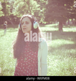 Vintage Hippie östliche frau mit Kopfhörer im Park Stockfoto