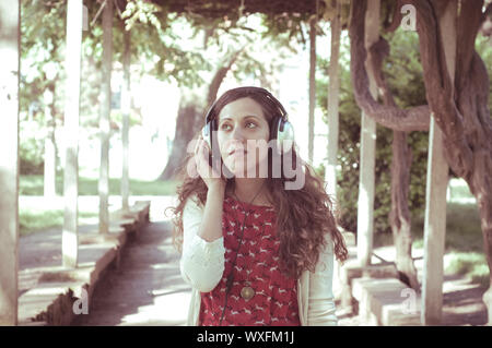 Vintage Hippie östliche frau mit Kopfhörer im Park Stockfoto