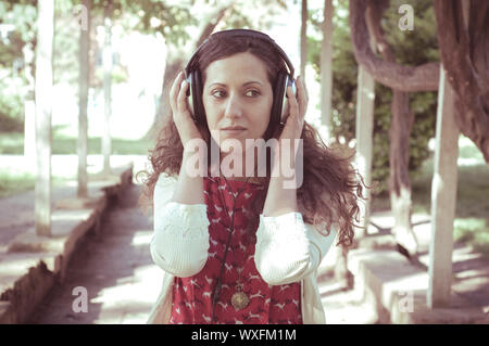 Vintage Hippie östliche frau mit Kopfhörer im Park Stockfoto