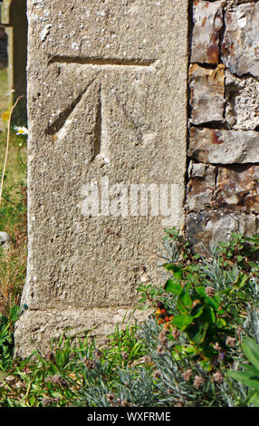 Eine Ordnance Survey Benchmark in Stein an der südwestlichen Ecke der Kirche der Heiligen Dreifaltigkeit in Ingham, Norfolk, England, UK, Europa. Stockfoto