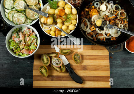 Gemüse auf dem Hintergrund. Gebratene zucchini Sauce in einen Teller. Junge gekochte Kartoffeln mit Dill in eine Schüssel geben. Gebratene Pfifferlinge Brei Stockfoto