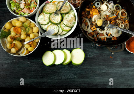 Gemüse auf dem Hintergrund. Gebratene zucchini Sauce in einen Teller. Junge gekochte Kartoffeln mit Dill in eine Schüssel geben. Gebratene Pfifferlinge Brei Stockfoto