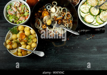 Gemüse auf dem Hintergrund. Gebratene zucchini Sauce in einen Teller. Junge gekochte Kartoffeln mit Dill in eine Schüssel geben. Gebratene Pfifferlinge Brei Stockfoto