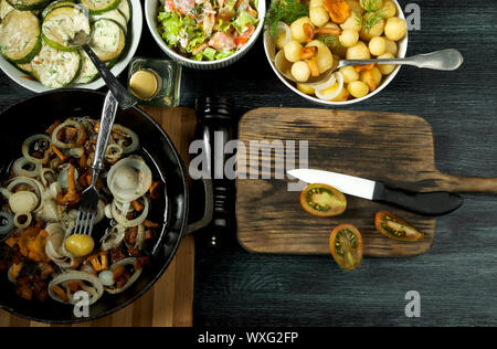 Gemüse auf dem Hintergrund. Gebratene zucchini Sauce in einen Teller. Junge gekochte Kartoffeln mit Dill in eine Schüssel geben. Gebratene Pfifferlinge Brei Stockfoto