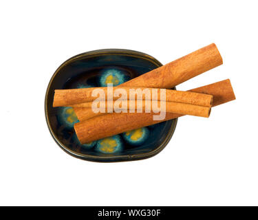 Trockene Zimtstangen in einer Schüssel auf einem weißen Hintergrund. Gewürz zu isolieren. Blick von oben. Nahaufnahme von Zimt. Stockfoto