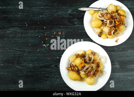 Gemüse auf dem Hintergrund. Junge gekochte Kartoffeln mit Dill in eine Schüssel mit gebratenen Pfifferlingen mit goldenen Zwiebeln auf ein Stockfoto