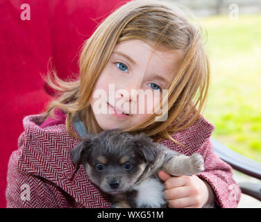 Blondes Mädchen umarmen ein grauen Chihuahua-Hündchen mit Wintermantel Stockfoto