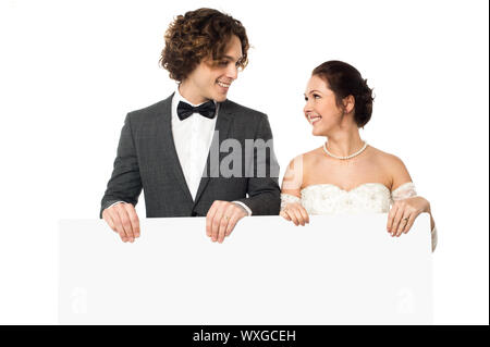 Frisch vermählte Paar posiert mit einer leeren weißen Tafel Stockfoto