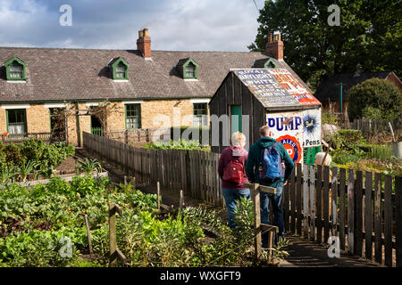 UK, County Durham, Beamish, Museum, Grube, Dorf, Francis Street, Besucher in der Miner cottage Gemüsegärten am Hut von altem Email Werbung Stockfoto