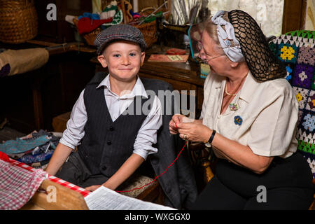 UK, County Durham, Beamish, Museum, Home Farm, junge Freiwillige gelehrt wird durch die Großmutter in Bauernhaus Küche zu häkeln Stockfoto