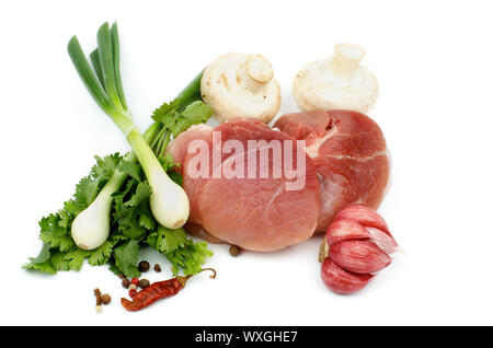 Perfekte Stück rohes Schweinefleisch ohne Knochen mit grünen, Frühlingszwiebeln, Gewürz- und essbaren Pilzen isoliert auf weißem Hintergrund Stockfoto