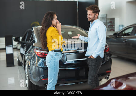 Schöne junge Paar Mann und Frau entscheiden, welches Auto Dealership Center auszuwählen. Stockfoto