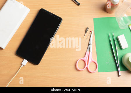 Telefon mit Power Bank auf dem Arbeitstisch Stockfoto