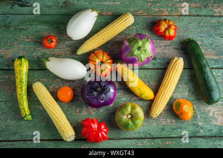 Vielfalt von bunten rote, grüne, gelbe, weiße, Tomaten, Zucchini, Mais und Auberginen über alten grünen Textur Hintergrund. Gesund essen Stockfoto