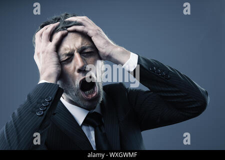 Eine schreiende besorgt, deprimiert und gestresst Geschäftsmann hält seinen Kopf Stockfoto