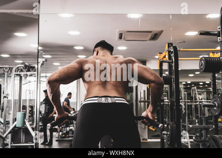 Muskulöse Männer trainieren mit Gewichten. Er ist der T-Bar rows für Rücken Muskeln Bodybuilder in der Turnhalle Stockfoto