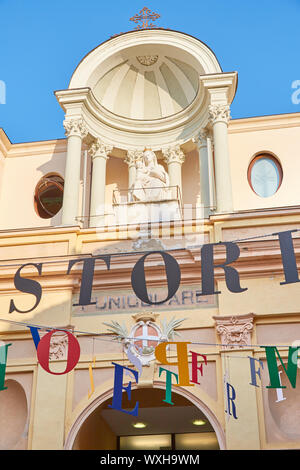 MONDOVI, Italien - 15. AUGUST 2016: Seilbahnstation Eingang mit beige Fassade und Jungfrau Maria Statue an einem sonnigen Sommertag in Mondovi, Italien. Stockfoto