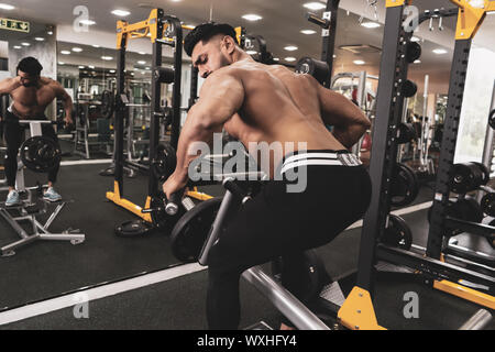 Muskulöse Männer trainieren mit Gewichten. Er ist der T-Bar rows für Rücken Muskeln Bodybuilder in der Turnhalle Stockfoto