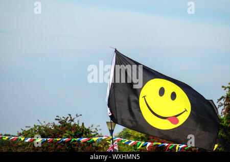 Gelbe lächelndes Gesicht Emoji auf einem Black Flag Stockfoto