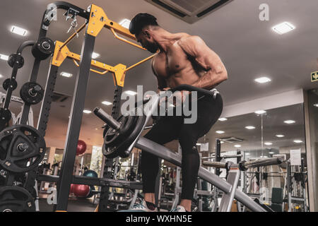 Muskulöse Männer trainieren mit Gewichten. Er ist der T-Bar rows für Rücken Muskeln Bodybuilder in der Turnhalle Stockfoto