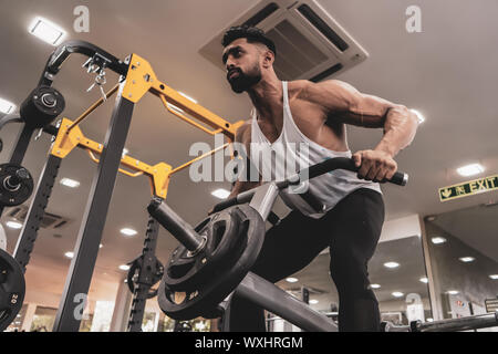 Muskulöse Männer trainieren mit Gewichten. Er ist der T-Bar rows für Rücken Muskeln Bodybuilder in der Turnhalle Stockfoto