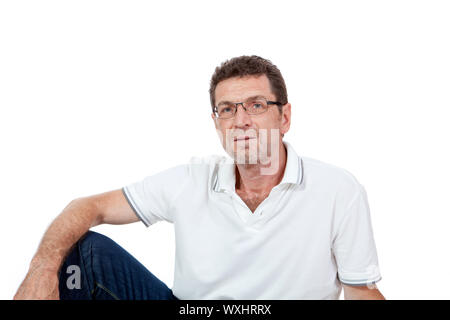 Attraktive gesunden erwachsenen Mann sitzt auf dem Boden mit Jeans isoliert Stockfoto