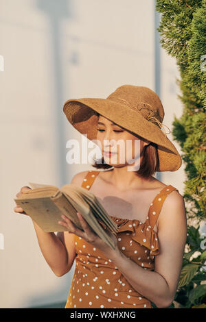 Portrait von jungen asiatischen Mädchen liest Buch im Park Stockfoto