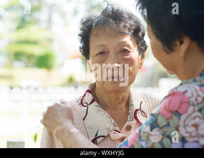 Reportageaufnahme einer reifen Frau trösten weinende alte Mutter bei Outdoor-Naturpark. Stockfoto