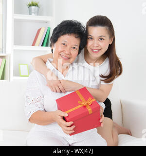Ältere Frau ein Geschenk von Erwachsenen Tochter, schöne asiatische Familie zu Hause erhalten. Stockfoto