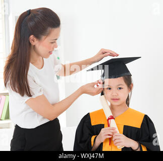 Asiatische Kind Graduierung, Lehrer Kappe für Schüler innen einstellen. Stockfoto