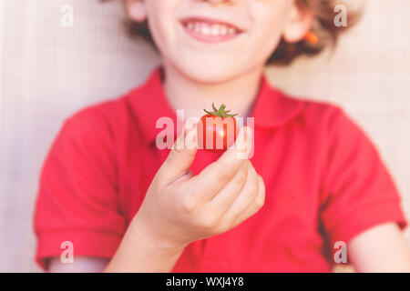 Lächelnde junge Holding eine Tomate Stockfoto